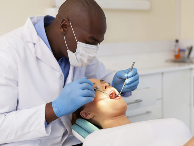 professional male dentist examining woman's teeth
